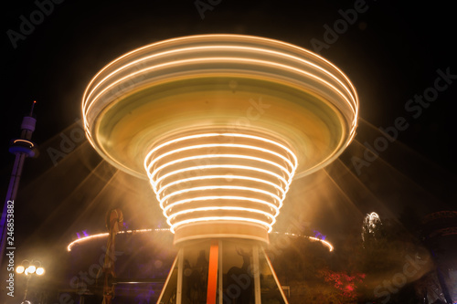 A blurry chain carousel in motion at the amusement park, night illumination. The effect of bokeh and long exposure.