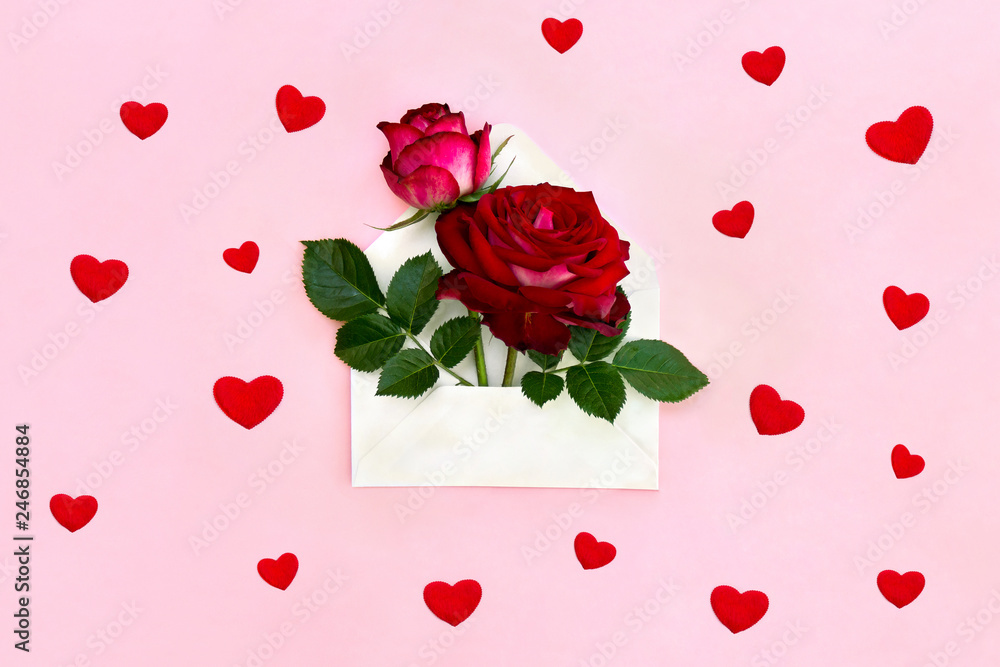 Decoration of Valentine Day. Beautiful flowers red roses in postal envelope on a pink paper background with hearts. Top view, flat lay