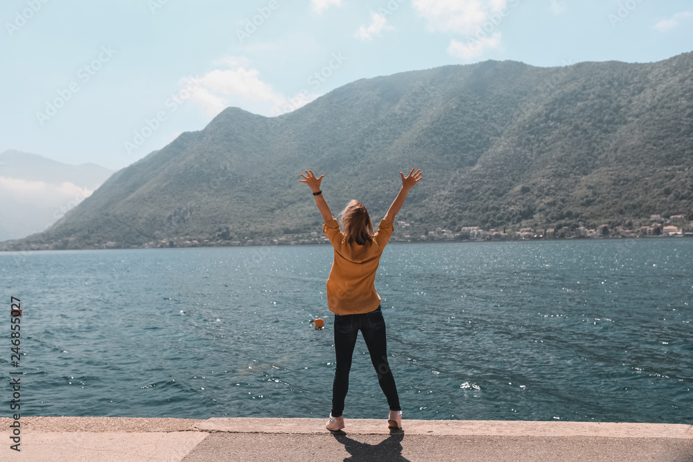 Obraz premium life style. travel and freedom. Hands up. Girl on the background of the mountains of Montenegro is standing, jumping in the old town by the sea