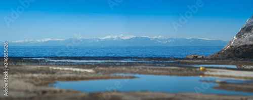 blue sea and reflective sky view of mountains snow hills at background at the...