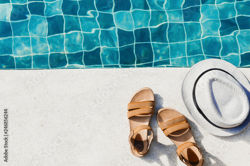 Vacation flat lay with woman's sandals and hat front of the pool
