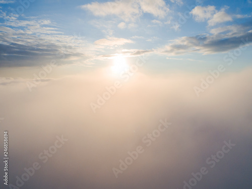 Aerial view White clouds in blue sky. Top view. View from drone. Aerial bird's eye view. Aerial top view cloudscape. Texture of clouds. View from above. Sunrise or sunset over clouds © Aleksei