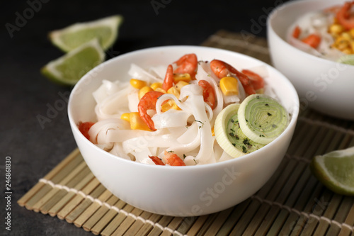 Bowl with rice noodles, shrimps and vegetables on table