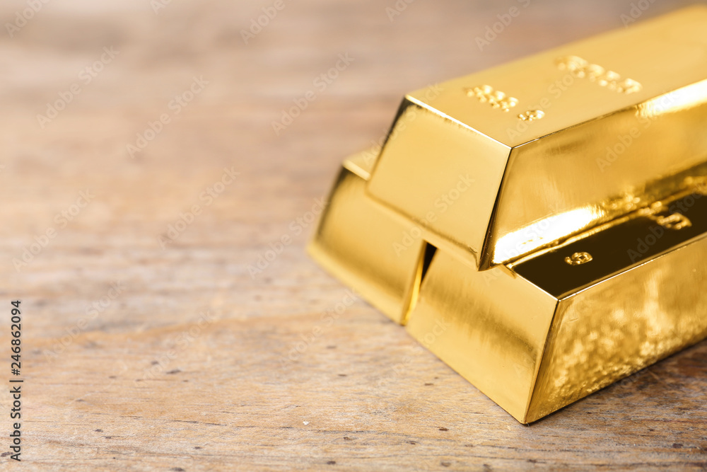 Shiny gold bars on wooden background. Space for text Shiny gold bars on wooden background. Space for text