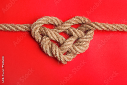 Heart made of rope on color background, top view