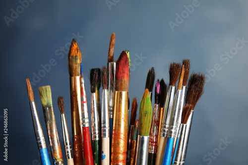 Different paint brushes on color background, closeup
