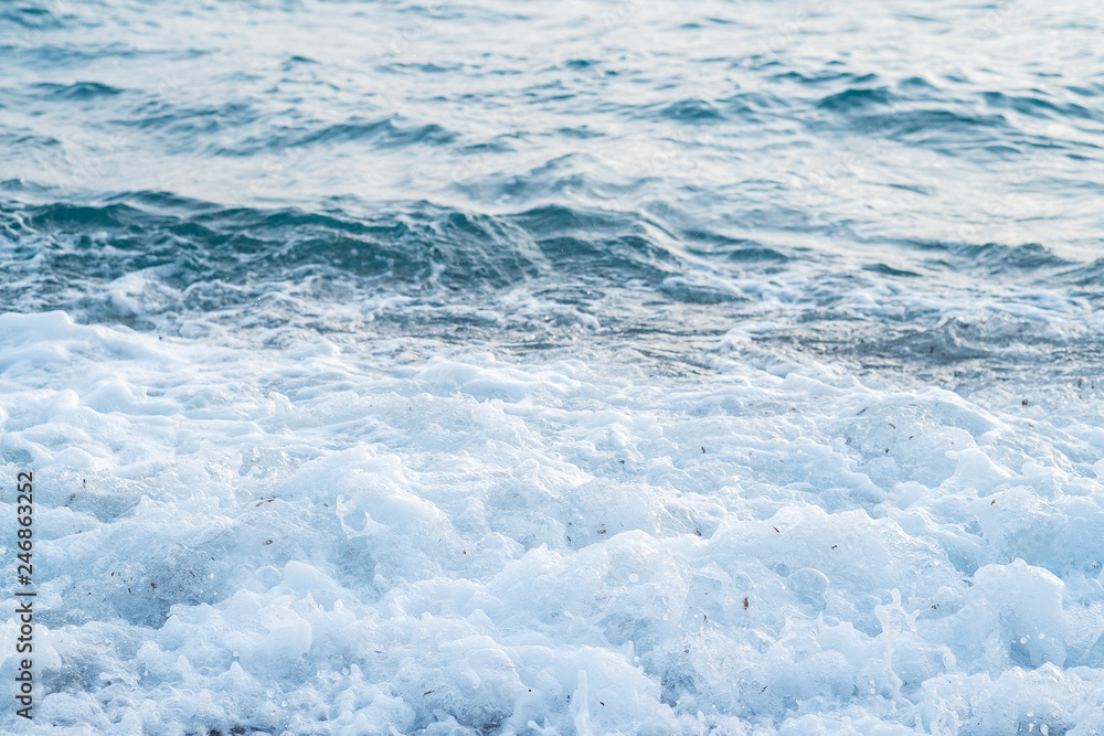 Sea waves in the sunset light roll on the seashore, covered with small pebbles Sea waves in the sunset light roll on the seashore, covered with small pebbles