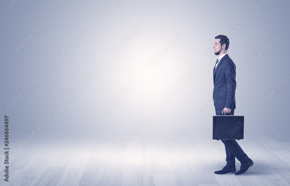 Successful businessman walking in front of an empty wall with briefcase on his hand
Successful businessman walking in front of an empty wall with briefcase on his hand