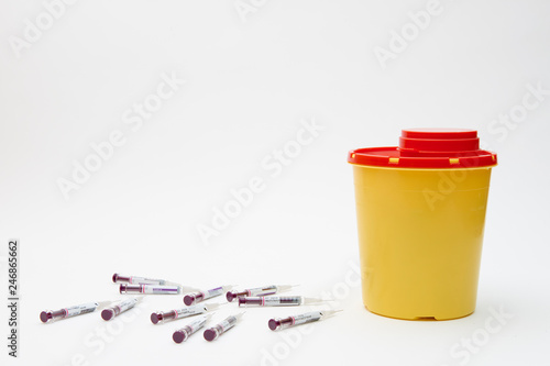 Needle and safety yellow bin over white background