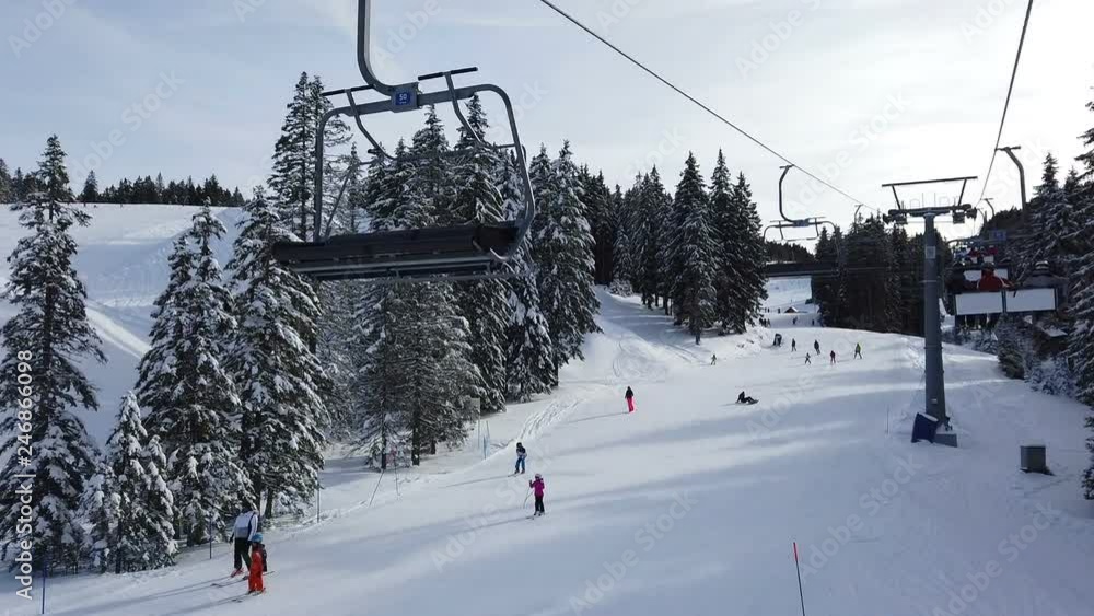 ROGLA, SLOVENIA, 2019.01.29: View from ski lift beside ski slope with skiers. Filming beautiful ski resort on cold sunny winter day. ROGLA, SLOVENIA, 2019.01.29: View from ski lift beside ski slope with skiers. Filming beautiful ski resort on cold sunny winter day.