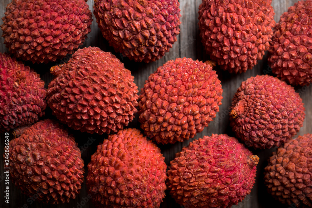 Red ripe lychees on the rustic background. Selective focus. Shallow depth of field. Red ripe lychees on the rustic background. Selective focus. Shallow depth of field.