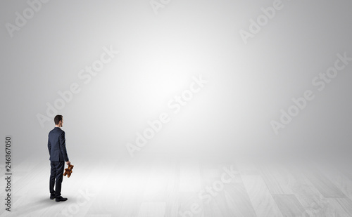 Man standing with his back in an empty room with object in his hand © ra2 studio