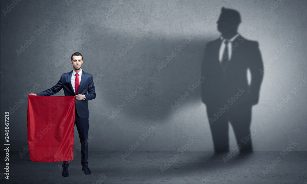Fototapeta premium Businessman standing with red cloth on his hand and his shadow on the background 