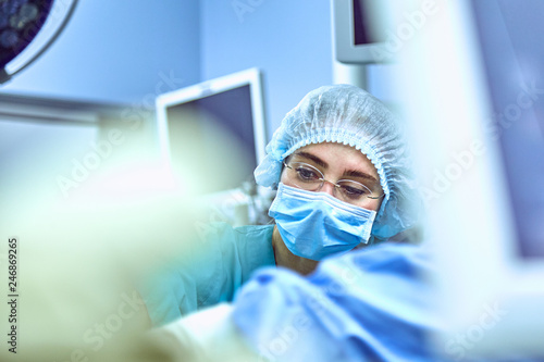 Young Female Surgeon with Medical Team in Back on Surgery