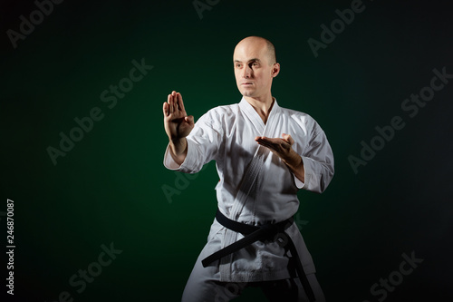 Active athlete trains formal karate exercises on a dark green background