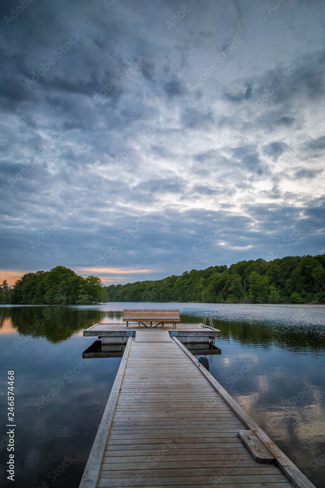 Wooden foot bridge leading out to a platform with a bench on a calm lake in Sweden Wooden foot bridge leading out to a platform with a bench on a calm lake in Sweden