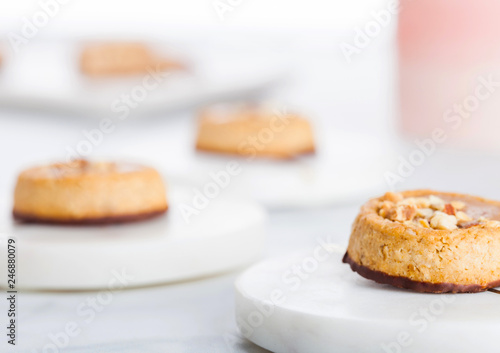 Homemade biscuit cookies with almond nuts and peanut butter on marble coasters on white kitchen table background.