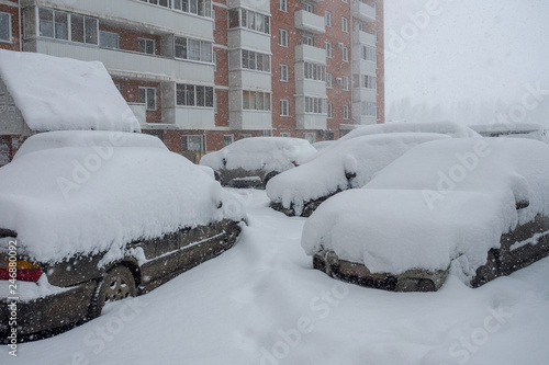 cars in the Parking lot in the city covered with a large layer of snow after abnormal snow precipitation