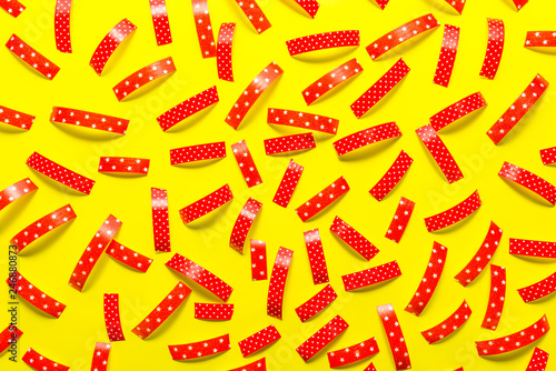 Pattern made from the red pieces of ribbons, isolated on a yellow background. View from the top.