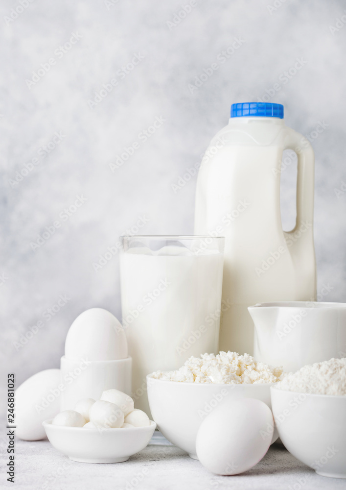 Fresh dairy products on white table background. Plastic bottle and glass of milk, bowl of cottage cheese and baking flour and mozzarella. Eggs and cheese. Fresh dairy products on white table background. Plastic bottle and glass of milk, bowl of cottage cheese and baking flour and mozzarella. Eggs and cheese.
