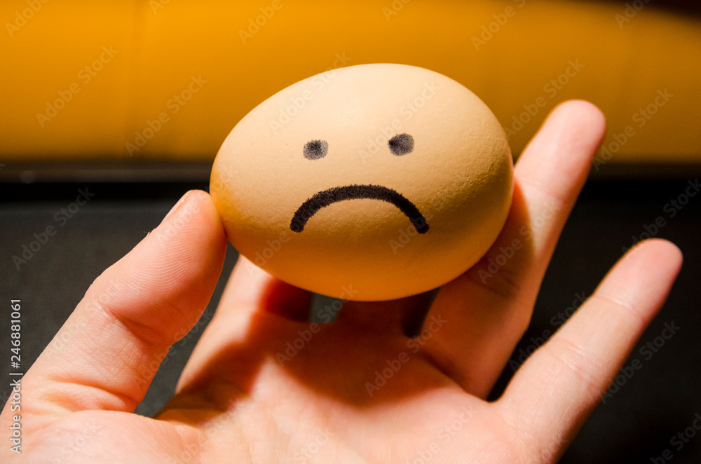 Egg with a sad smile in the hand of a person