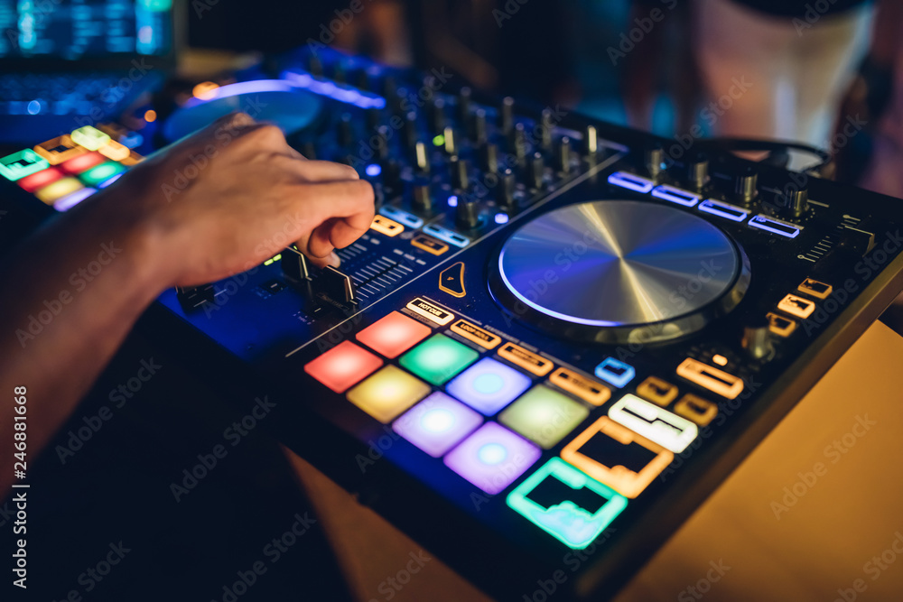 DJ plays live set and mixing music on turntable console at stage in the