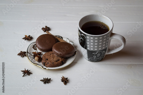 A cup of coffee with chocolate cookies, on a white wooden table.