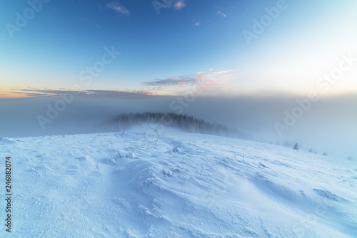 Evening winter landscape in the Ukrainian Carpathians with snow-capped peaks, fogs and beautiful skies.