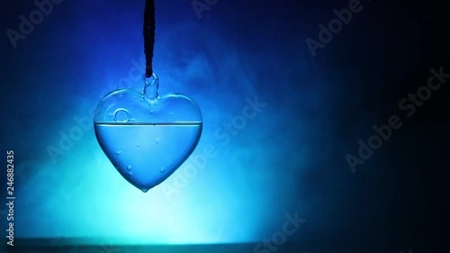 Valentines Day Concept. Glass transparent heart on dark, glass heart glows, glass painting, black background. Emptry space for your text photo