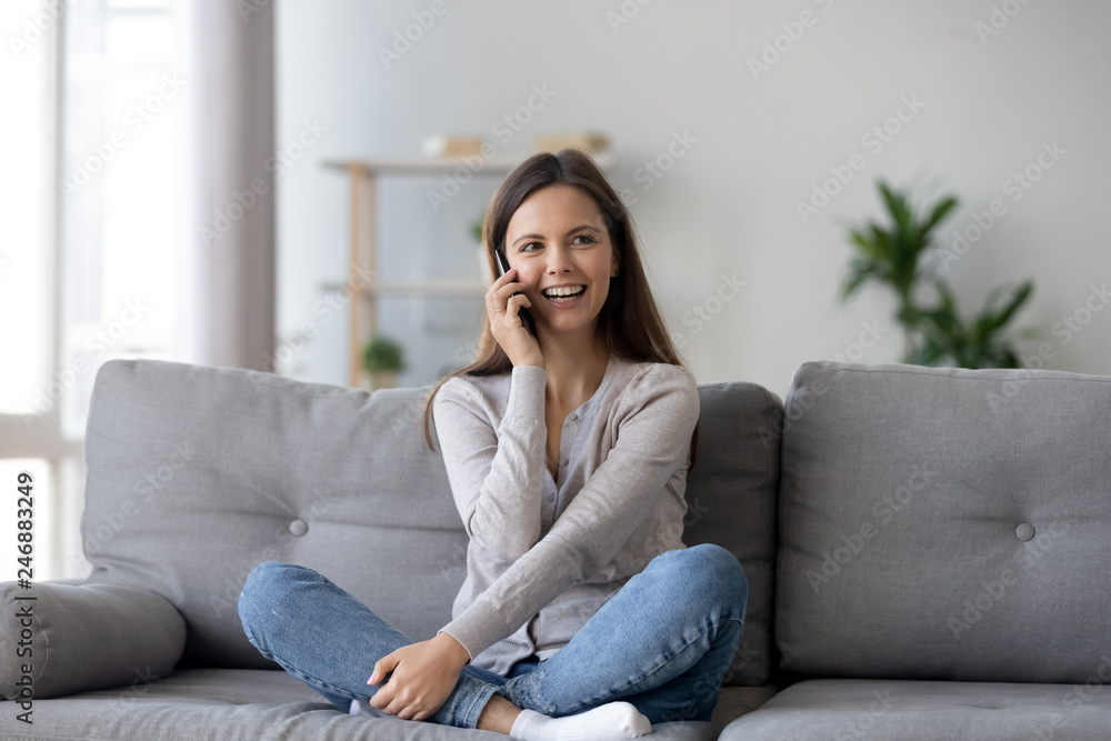 Happy young woman sit at table sew on machine at home. Smiling