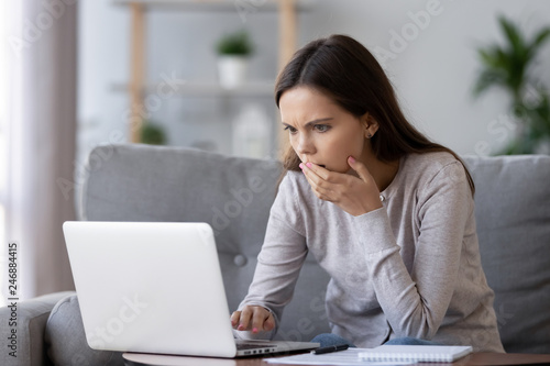 Shocked stressed young woman reading bad online news looking at broken laptop screen, confused teen girl in panic frustrated with stuck computer problem mistake virus, negative social media message photo