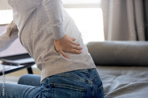 Rear close up view at woman touching aching back feeling lower lumbar muscular kidney pain rubbing tensed muscles suffering from backache sitting in sedentary incorrect posture, backpain concept photo
