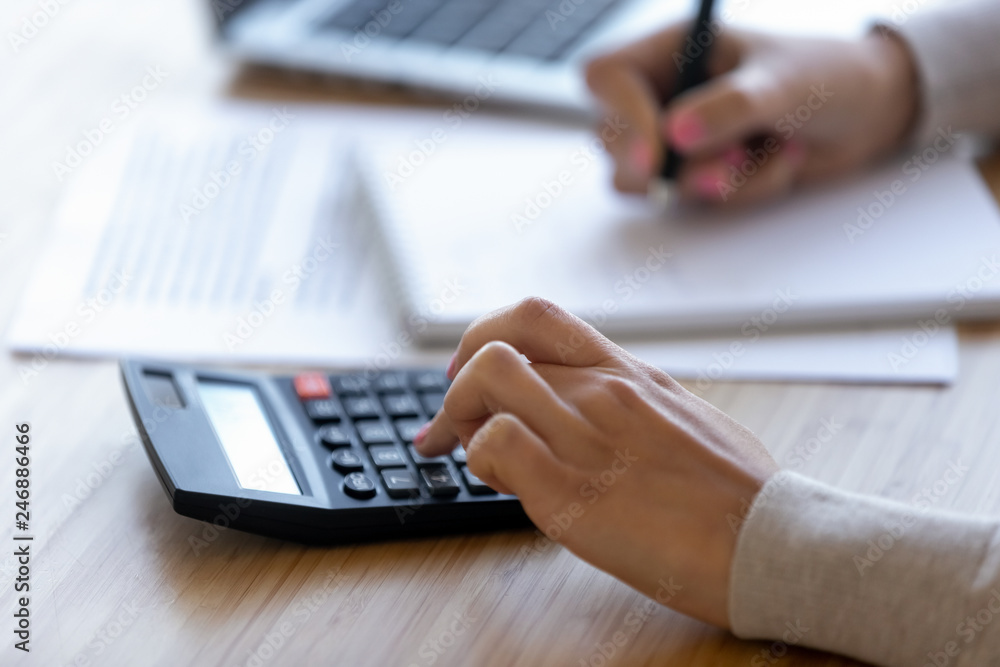 Female professional using calculator for business financial accounting, accountant or bookkeeper making calculations managing money, woman calculating bills expenses taxes making notes, close up view Female professional using calculator for business financial accounting, accountant or bookkeeper making calculations managing money, woman calculating bills expenses taxes making notes, close up view