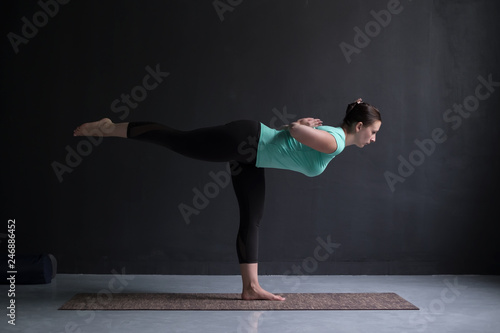 Sporty fit woman practices yoga asana Virabhadrasana 3