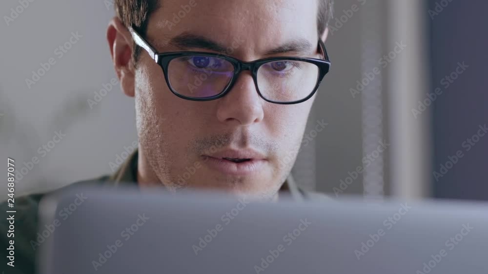 Close up of a young, caucasian businessman working on his laptop in a modern office Close up of a young, caucasian businessman working on his laptop in a modern office