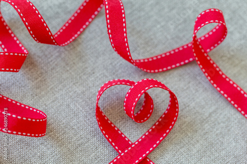 Heart made from red ribbon on linen fabric, Valentine's Day concept.