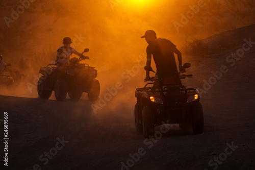 People enjoying driving atv on sunset in Valleys of Cappadocia with lot of dusts in background.