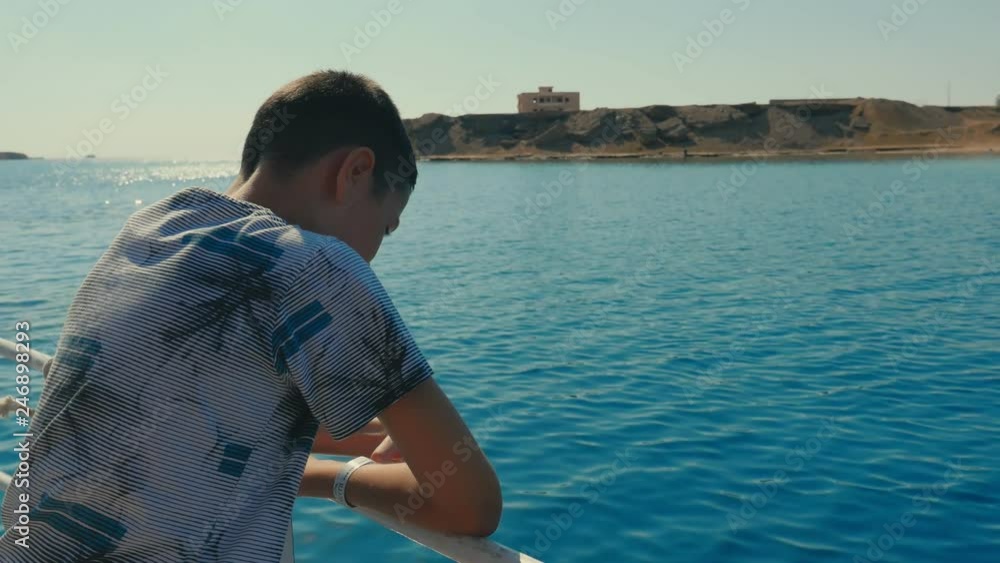 Small boy enjoys the rippling sea waves leaning on touristic ship rails in Egypt Small boy enjoys the rippling sea waves leaning on touristic ship rails in Egypt