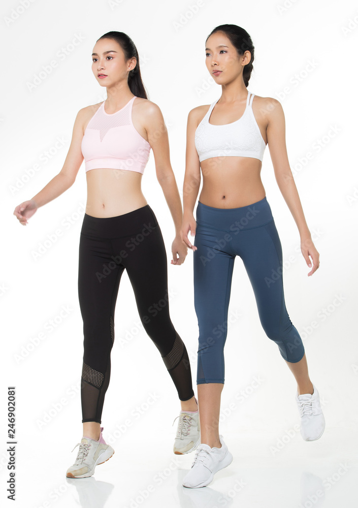 Two Asian Tan Skin Fitness women exercise wear pink blue black bra pant suit gear jump walk cross in the air white background, studio lighting copy space isolated, concept 2 Woman motion blur hands Two Asian Tan Skin Fitness women exercise wear pink blue black bra pant suit gear jump walk cross in the air white background, studio lighting copy space isolated, concept 2 Woman motion blur hands