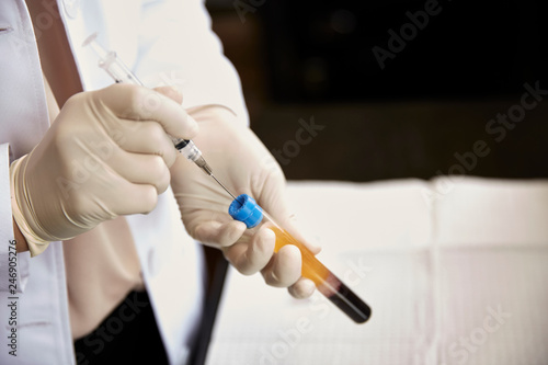 Female doctor taking blood with syringe from vial