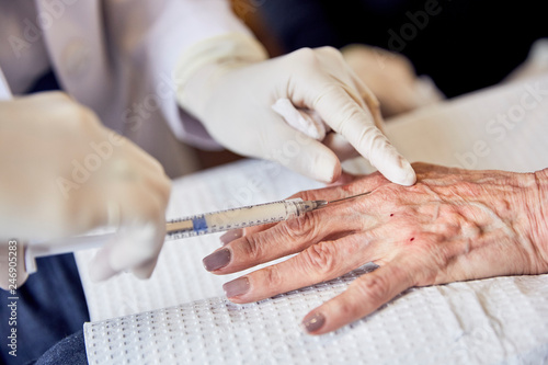 Female doctor injecting senior woman in clinic photo