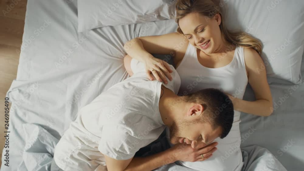 Happy Young Couple Cuddling Together in the Bed, Young Woman is Pregnant, Loving Partner Leans and Listens to a Baby Moving and it's Heartbeat in the Belly. Tender and Loving Moments of Family Life. Happy Young Couple Cuddling Together in the Bed, Young Woman is Pregnant, Loving Partner Leans and Listens to a Baby Moving and it's Heartbeat in the Belly. Tender and Loving Moments of Family Life.