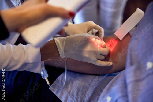 Female phlebotomist drawing blood with vein finder