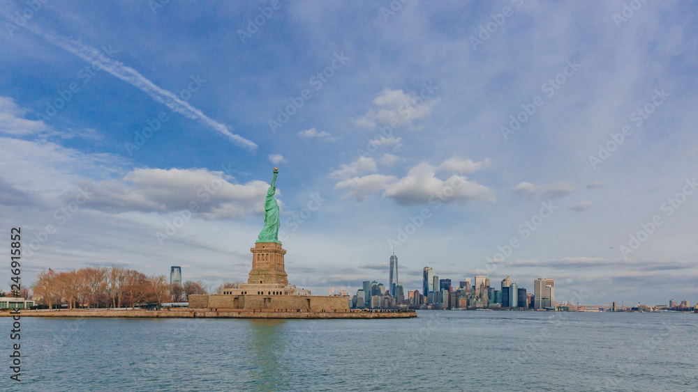 Statue of Liberty overlooking buildings of downtown Manhattan by water, in New York City, USA Statue of Liberty overlooking buildings of downtown Manhattan by water, in New York City, USA