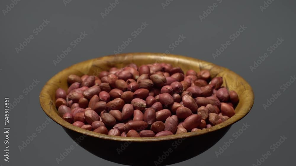 Raw unpeeled peanuts. Rotation. Snack closeup. Peanuts in a bowl. Selective focus. grey background. Studio shot. Healthy food concept. Raw unpeeled peanuts. Rotation. Snack closeup. Peanuts in a bowl. Selective focus. grey background. Studio shot. Healthy food concept.