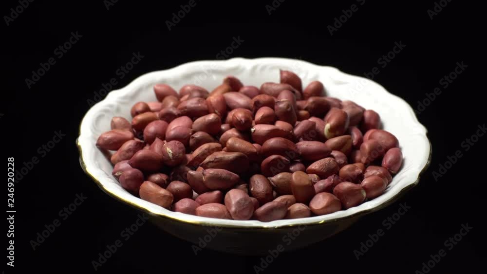 Raw unpeeled peanuts. Rotation. Snack closeup. Peanuts in a bowl. Selective focus. black background. Studio shot. Healthy food concept. Raw unpeeled peanuts. Rotation. Snack closeup. Peanuts in a bowl. Selective focus. black background. Studio shot. Healthy food concept.