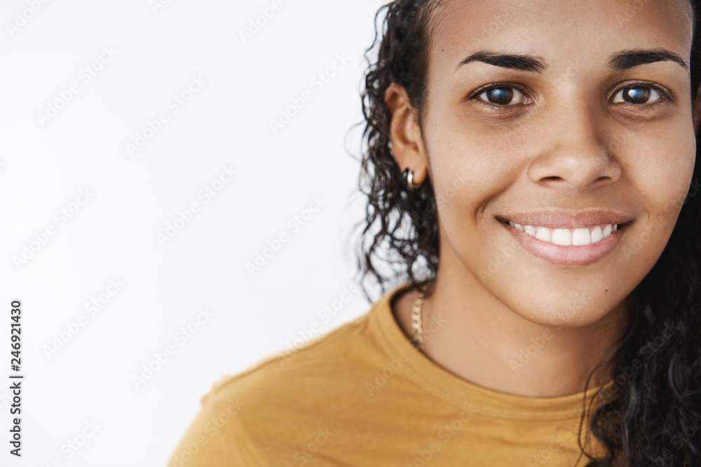 Close-up shot of smiling happy and delighted friendly-looking african-american woman with curly hair in mustard t-shirt grinning and gazing at camera expressing good confident vibes Close-up shot of smiling happy and delighted friendly-looking african-american woman with curly hair in mustard t-shirt grinning and gazing at camera expressing good confident vibes