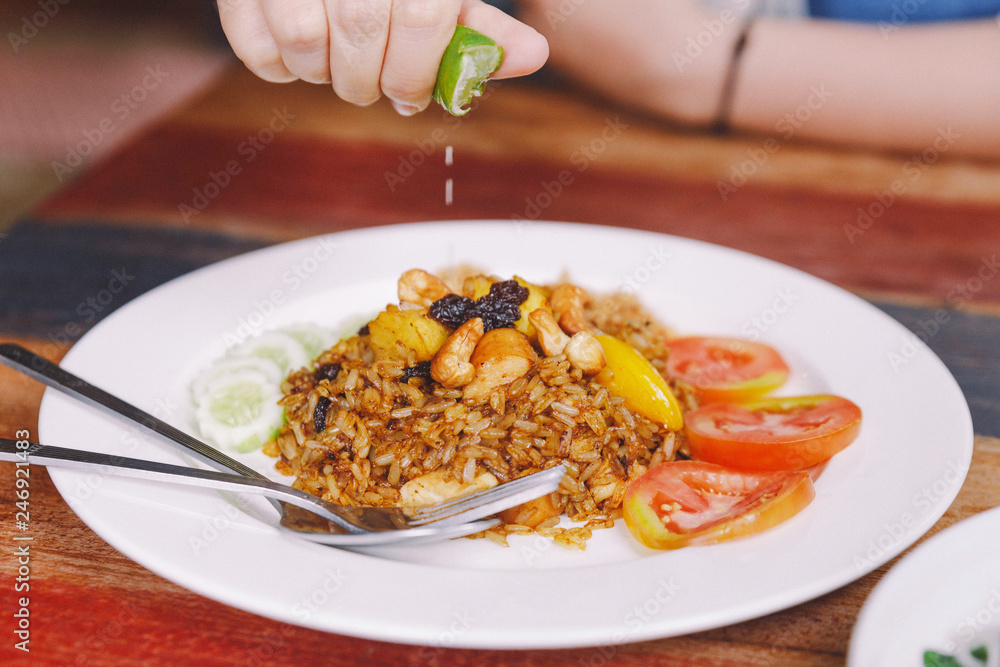 Close up Thai Pineapple Fried Rice topping with raisin, cashews and dried shredded pork. Served with cucumber and tomato and hand squeezing lime. Close up Thai Pineapple Fried Rice topping with raisin, cashews and dried shredded pork. Served with cucumber and tomato and hand squeezing lime.