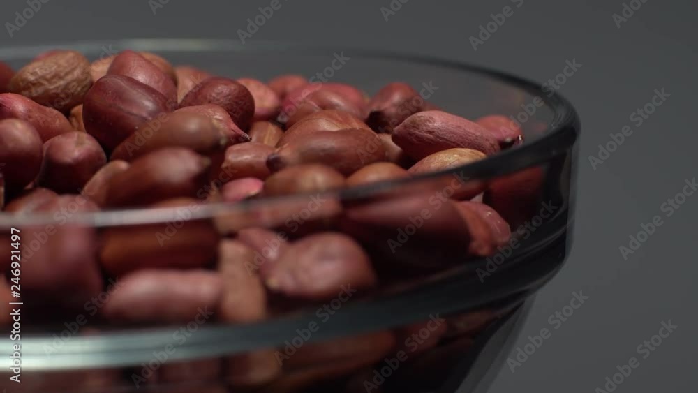 Raw unpeeled peanuts. Rotation. Snack closeup. Peanuts in a bowl. Selective focus. grey background. Studio shot. Healthy food concept. Raw unpeeled peanuts. Rotation. Snack closeup. Peanuts in a bowl. Selective focus. grey background. Studio shot. Healthy food concept.