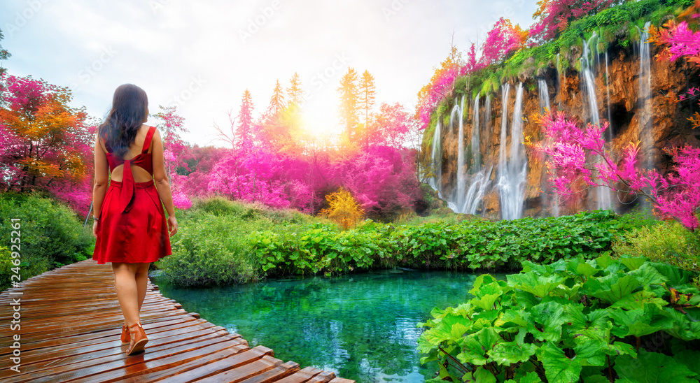 Fototapeta Woman traveler walking on wooden path trail with lakes and waterfall landscape in Plitvice Lakes National Park, UNESCO natural world heritage and famous travel destination of Croatia.